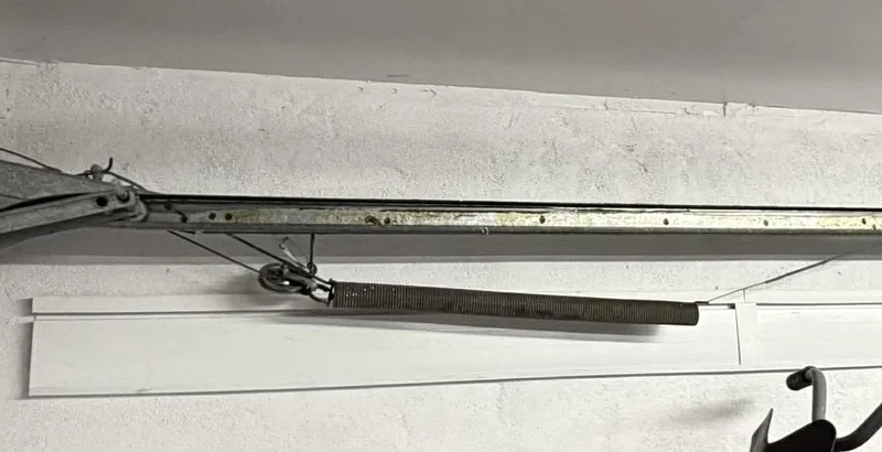 Extension spring mounted beside a garage door track