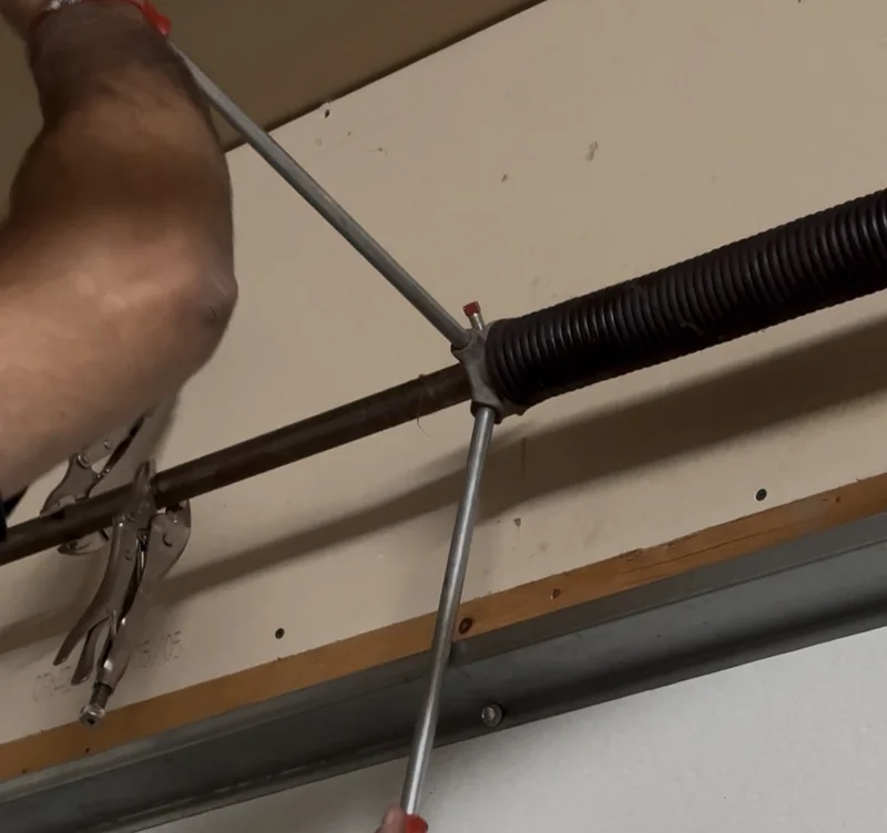 Technician adjusting a torsion spring during garage door spring repair